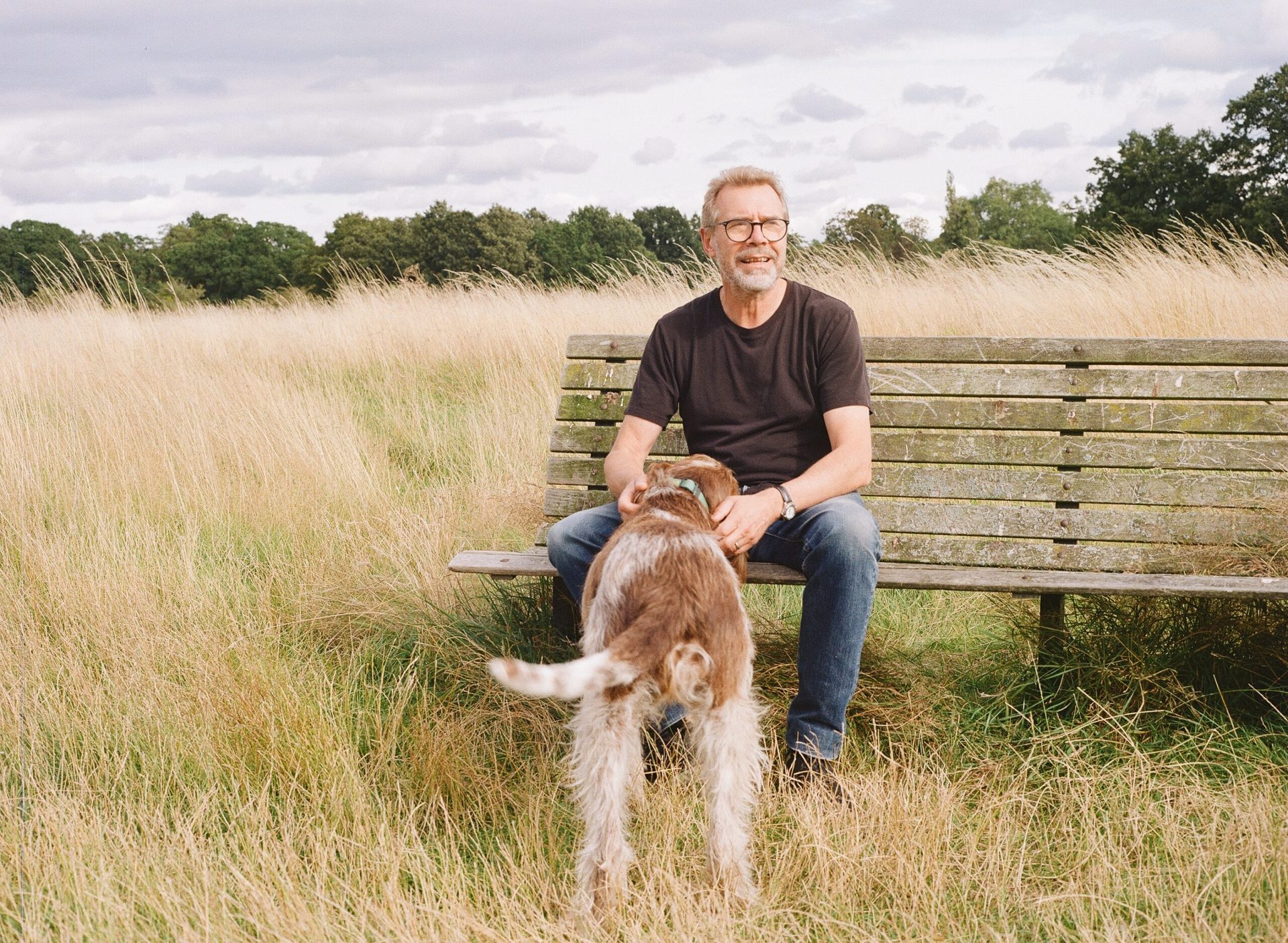 Ian Cross, founder of Food Bench, sitting on a wooden bench with his dog
