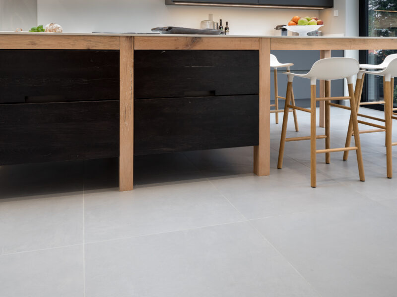 End view of a medium oak island with white bar stools in bright natural light