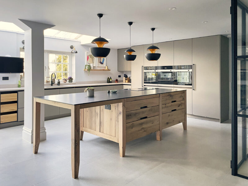 Dark-stained oak island with white worktop and black cabinetry, garden view beyond