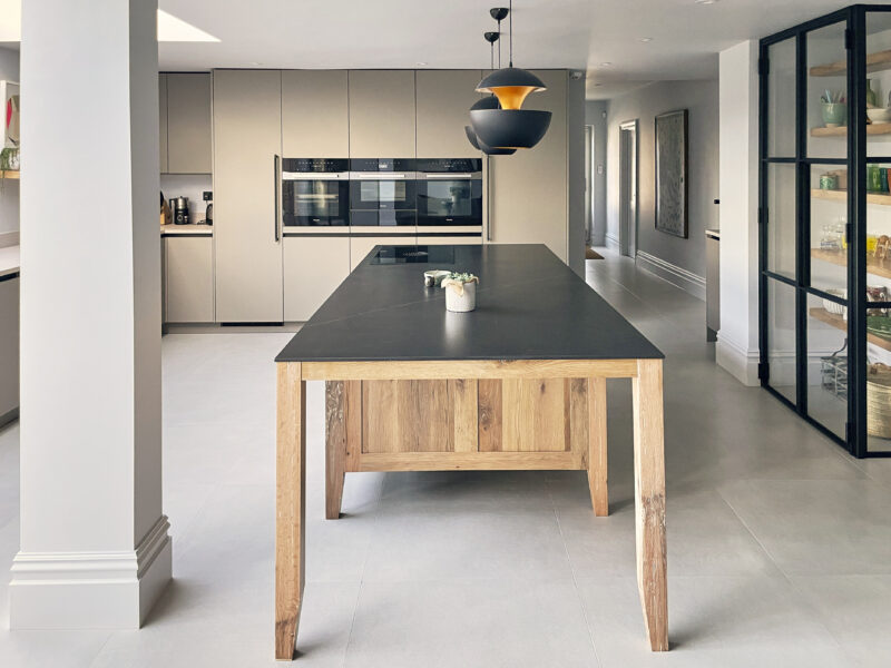 Medium oak island with dark grey worktop and polished concrete floor in a minimal kitchen