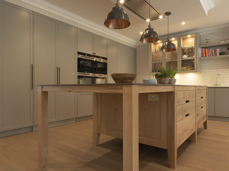 Pale oak island with grey-taupe worktop against cream cabinetry and a white backsplash